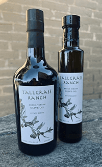 2 bottles of olive oil in front of a brick wall